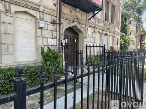 A black wrought iron fence in front of a building with a red awning.
