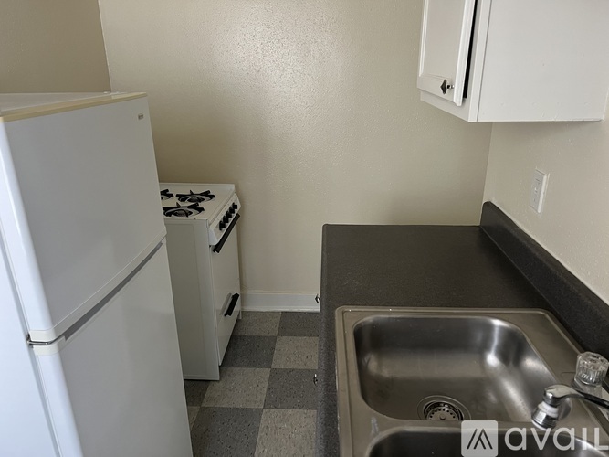 A small kitchen with a white fridge, a stove, and a sink.