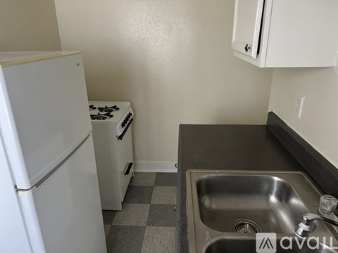 A small kitchen with a white fridge, a stove, and a sink.