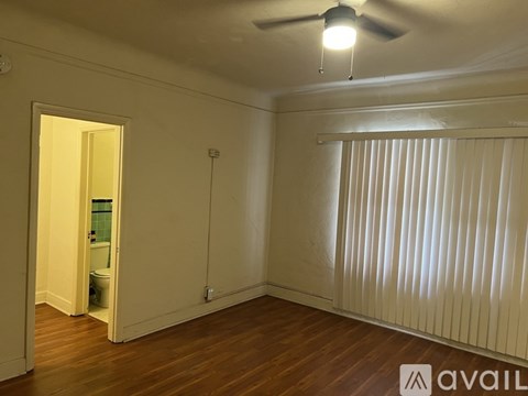 A room with a ceiling fan and a window with blinds.
