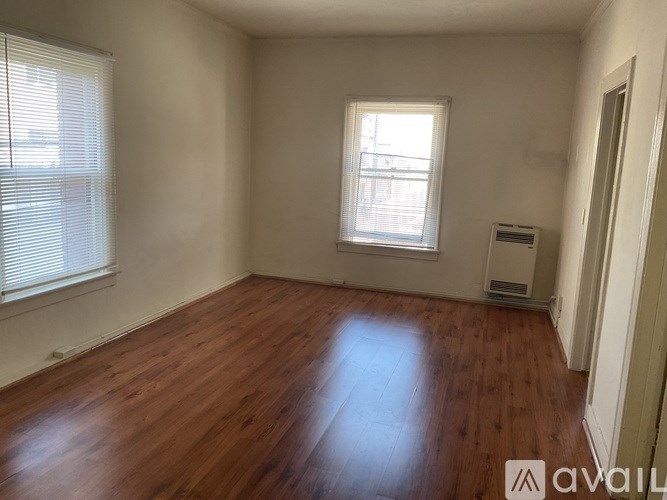 A room with wooden flooring and a window with blinds.