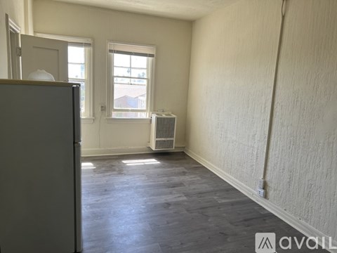 A room with a grey floor and white walls, with a window and a radiator.