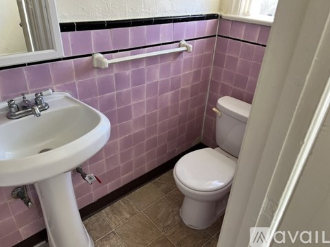 A white sink is on the left of a toilet in a pink tiled bathroom.