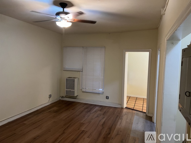 A room with a ceiling fan and a window with blinds.