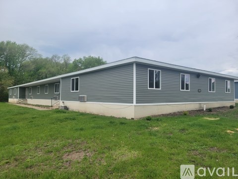 A grey building with a metal roof and a grassy area in front.