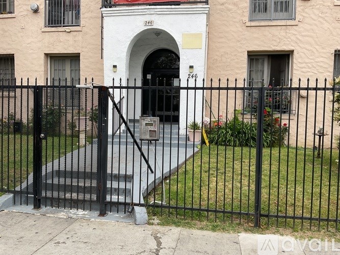 A black iron fence surrounds a white building with a black gate.