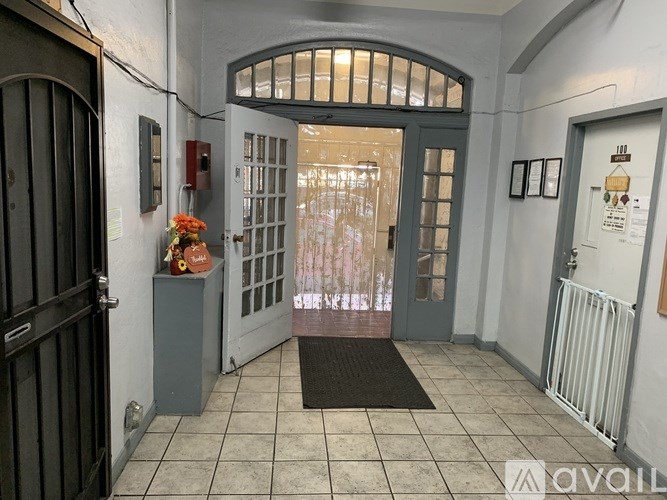 A hallway with a black door on the left and a glass door in the middle.