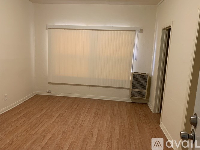 A room with wooden flooring and a window with blinds.