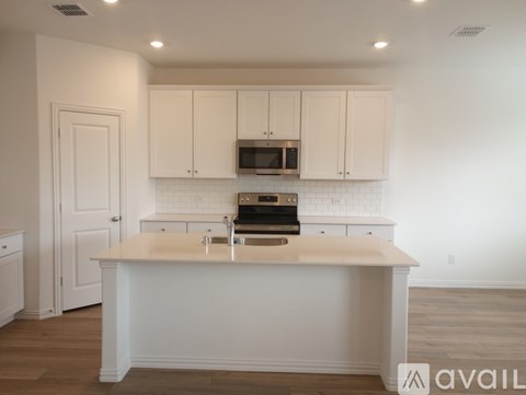 A kitchen with white cabinets and a white island.