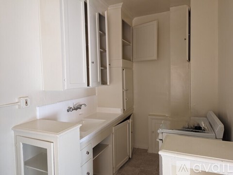 A white kitchen with a sink and cabinets.