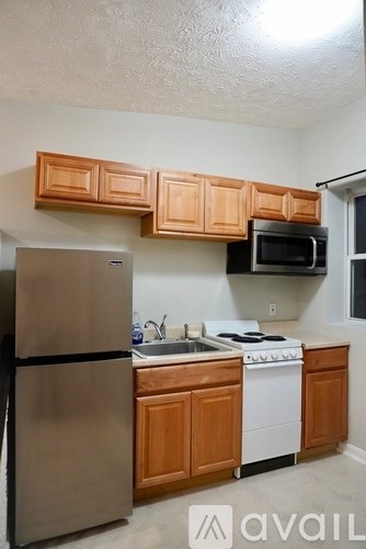 A kitchen with wooden cabinets and a stainless steel refrigerator.