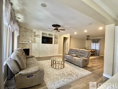 A living room with a grey sofa and a white ceiling fan.