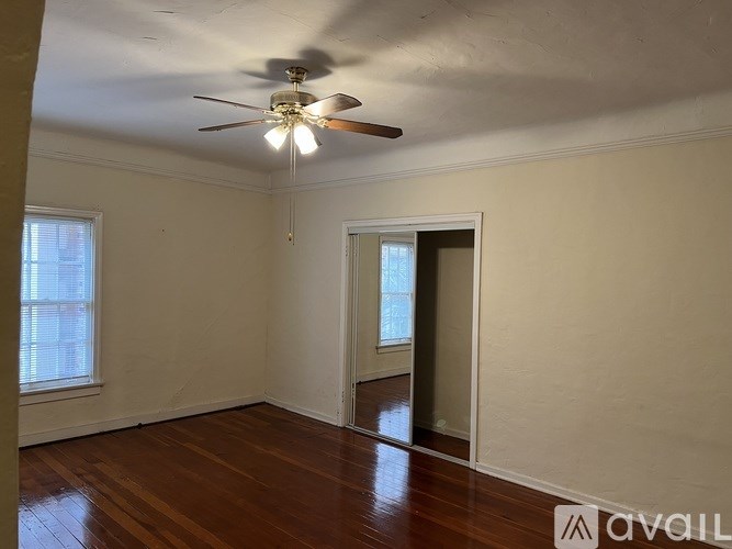 A room with a ceiling fan and wooden floors.
