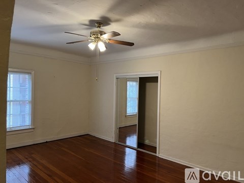 A room with a ceiling fan and wooden floors.