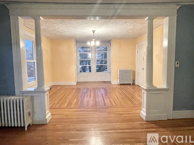 A spacious room with wooden floors and white columns.