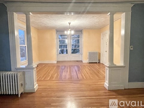 A spacious room with wooden floors and white columns.