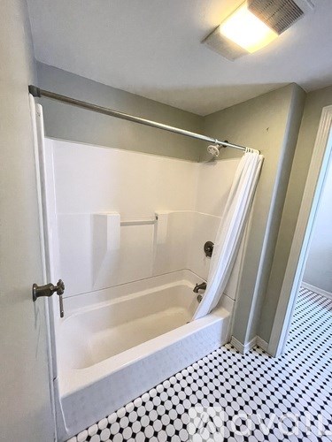 A white and black tiled bathroom with a glass shower door.