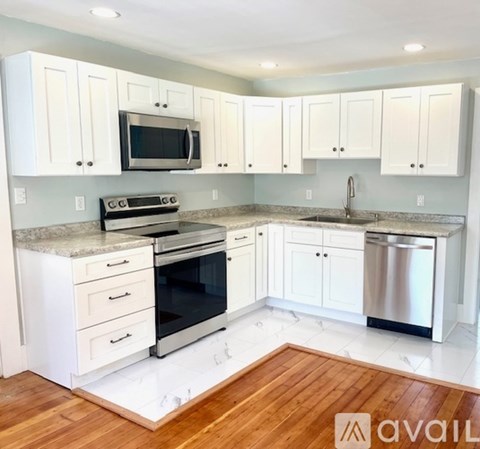 A kitchen with white cabinets and a wooden floor.