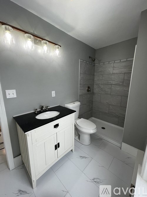 A bathroom with a black countertop and white fixtures.