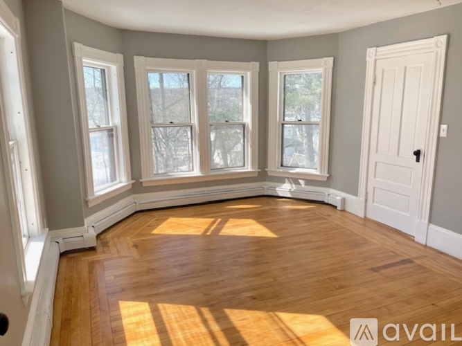 A room with wooden floors and three windows.