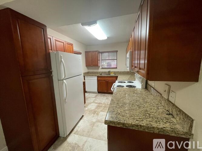 A kitchen with a granite countertop and wooden cabinets.