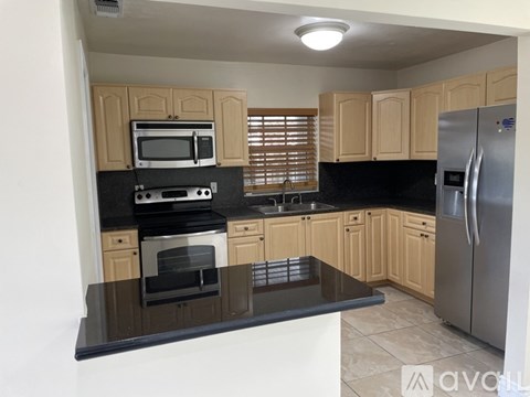 A kitchen with wooden cabinets and black countertops.