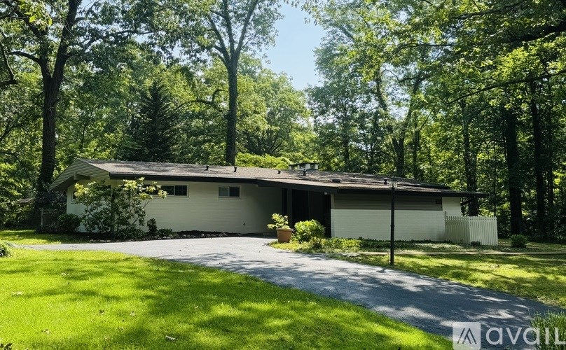 A house with a white exterior is surrounded by greenery.