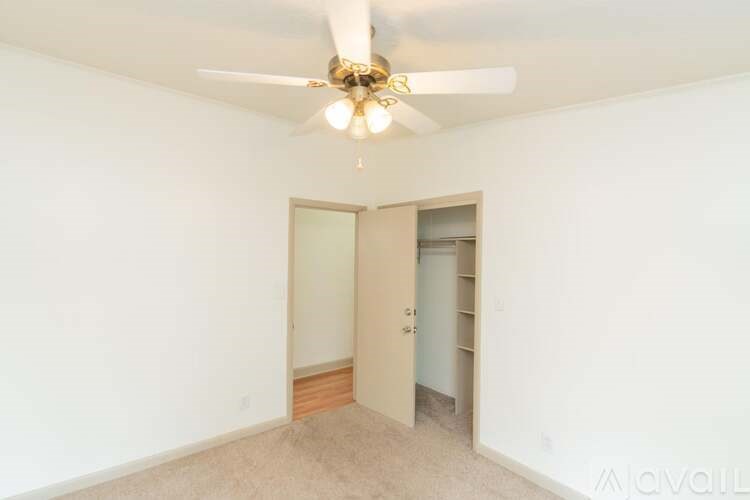 A room with a ceiling fan and a door leading to another room.