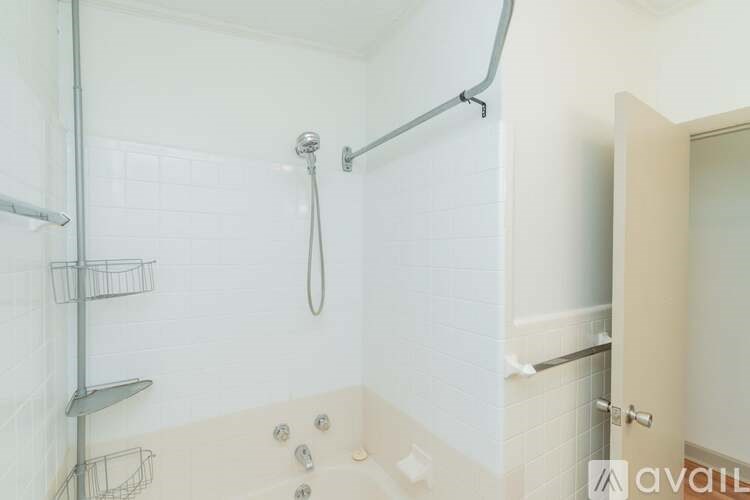 A white tiled bathroom with a shower and a door.