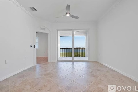 A spacious room with a fan and a sliding glass door leading to a balcony.