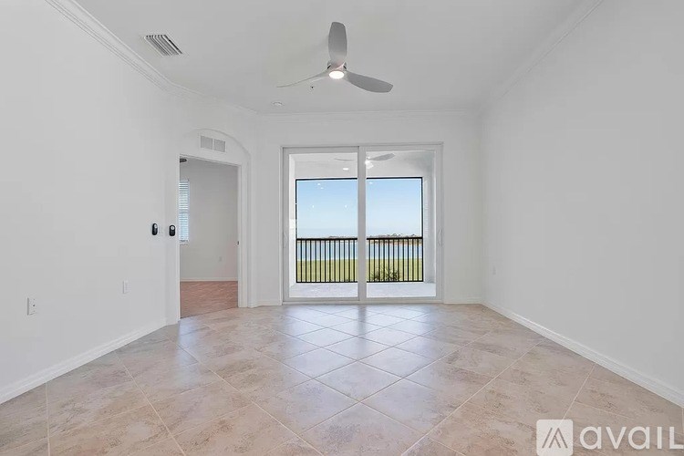 A spacious room with a fan and a sliding glass door leading to a balcony.