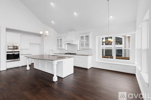 A modern kitchen with white cabinets and a wooden floor.