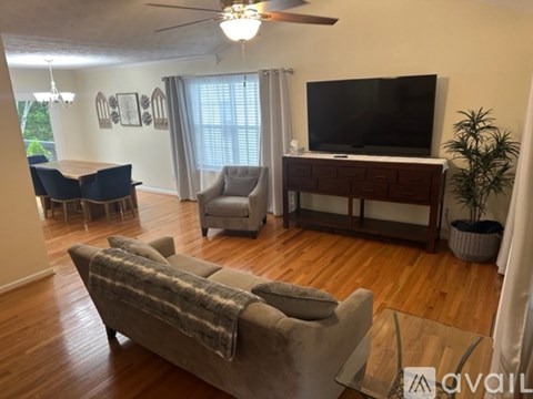 A living room with a grey couch and a television on a wooden stand.