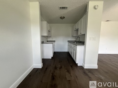 A kitchen with white cabinets and a wooden floor.