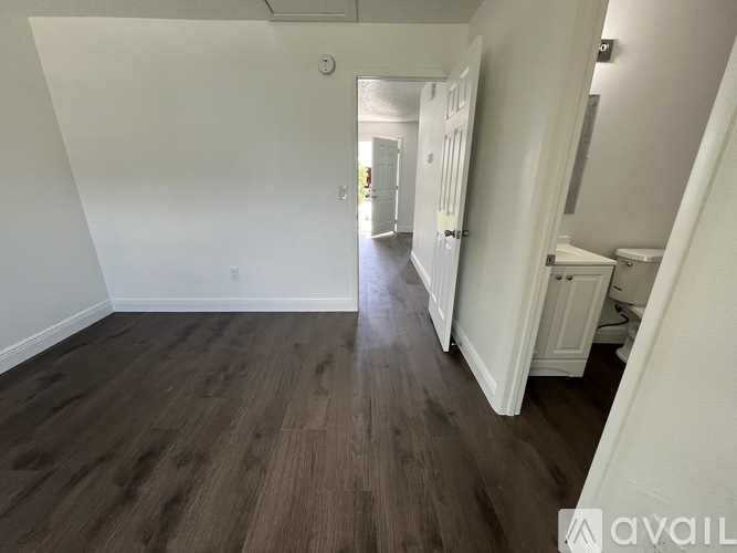 A hallway with wood flooring and white walls.