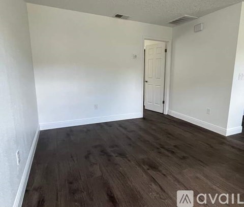 A hallway with wood flooring and white walls.