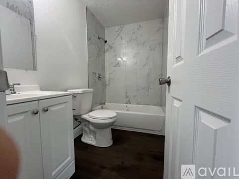 A white bathroom with a toilet, sink, and bathtub.