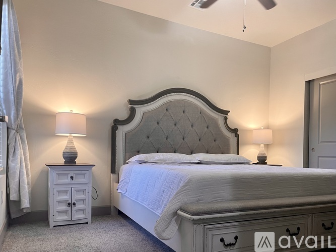 A bedroom with a large bed and a nightstand with a lamp.