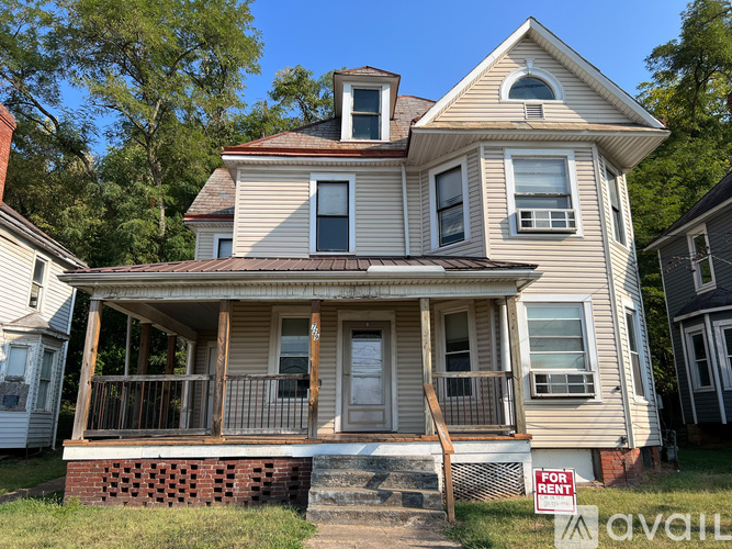 A house with a porch and a "For Rent" sign in front.