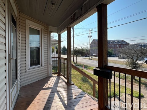 A porch with a view of the street and houses.