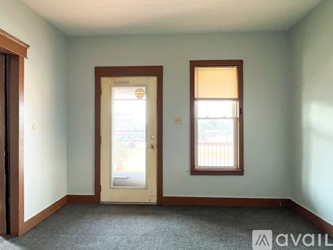 A room with a carpeted floor, two doors, and two windows.