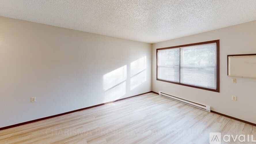 A room with wooden flooring and a window with blinds.