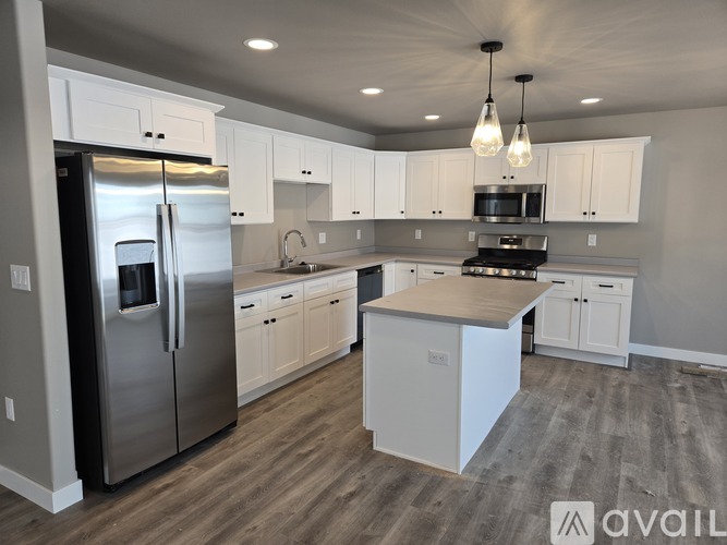 A modern kitchen with white cabinets and a stainless steel refrigerator.