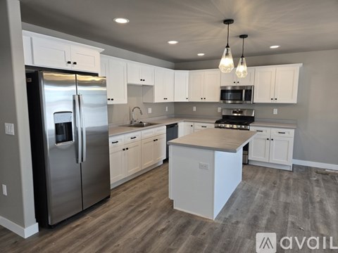 A modern kitchen with white cabinets and a stainless steel refrigerator.
