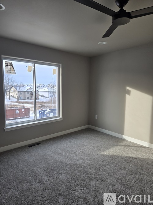 A room with a ceiling fan and a large window overlooking a snowy landscape.