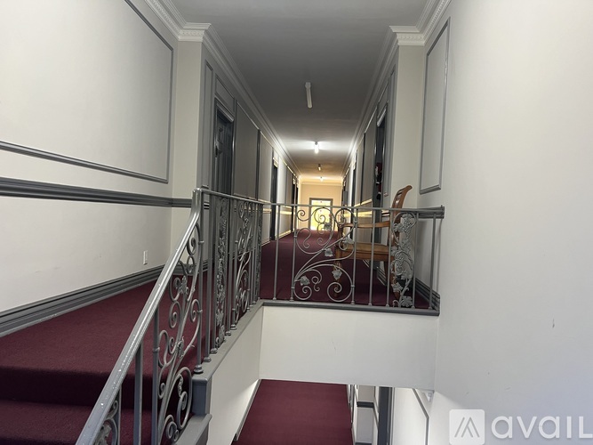 A staircase with a red carpet and metal railing.