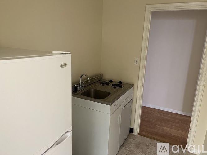 A small kitchen with a white fridge, sink and cabinets.
