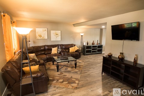 A living room with a brown leather couch and a television on the wall.