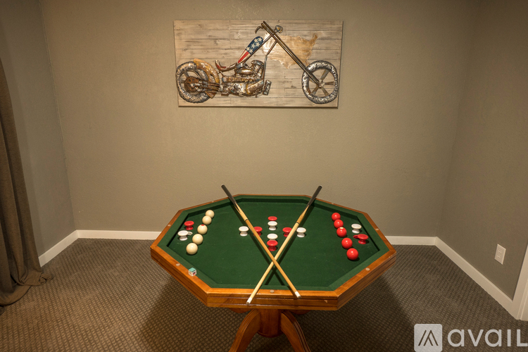 A pool table with a green felt top and white balls is in the center of the image.
