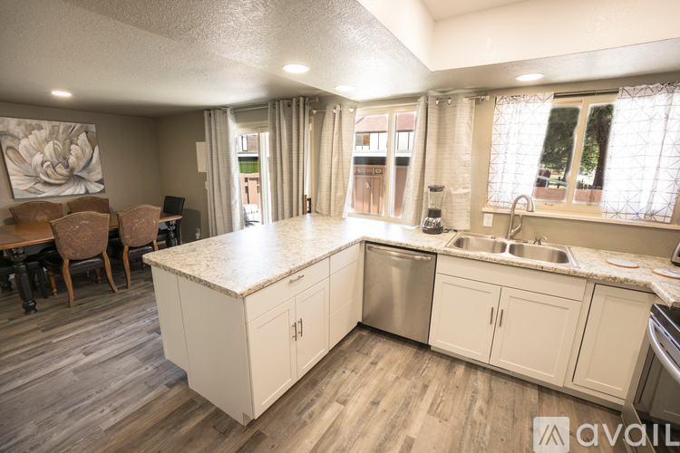 A kitchen with white cabinets and a wooden floor.